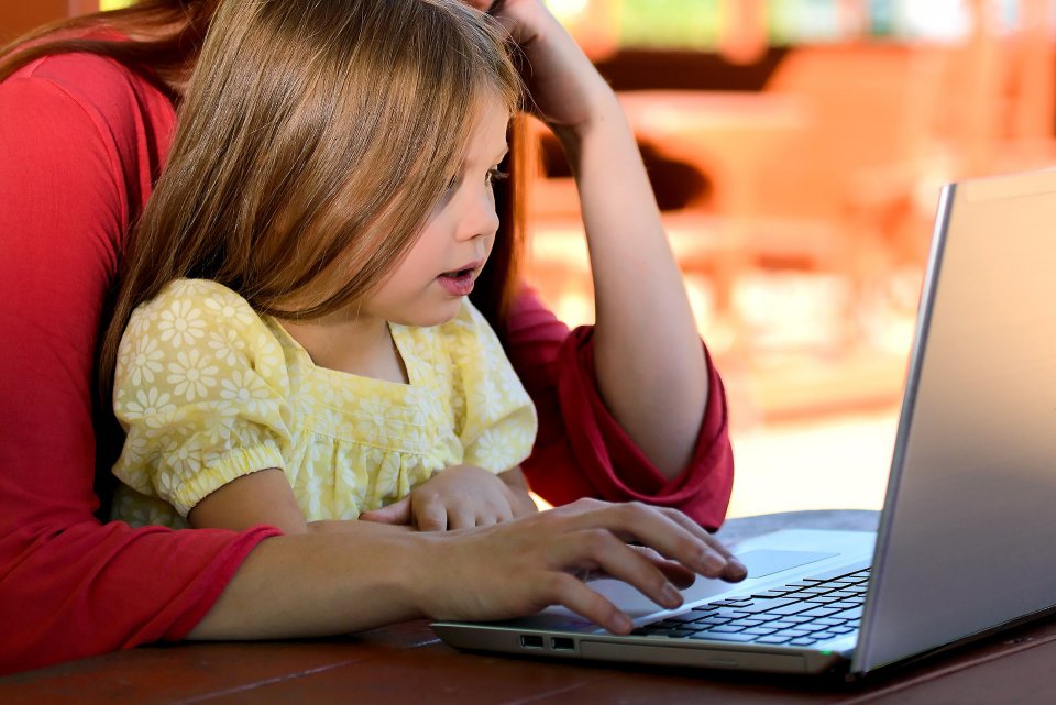 Parent helps child on laptop