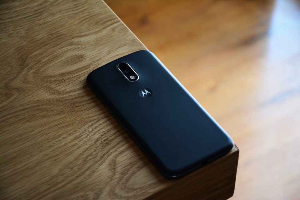 A Motorola smartphone laying on the corner of a wooden table
